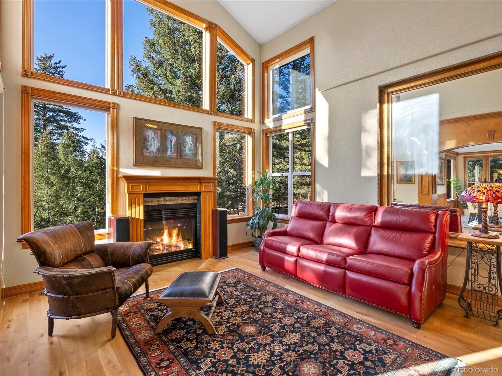 20906 Horse-Bit Way Morrison, CO 80465 - Photo 10 of 49 a living room with furniture a fireplace and floor to ceiling windows