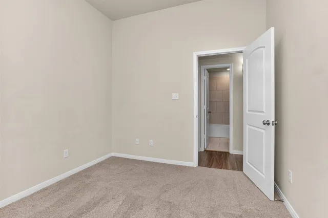 a view of an empty room with closet and mirror