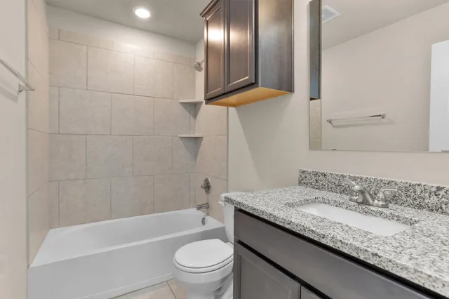 a bathroom with a granite countertop sink a toilet and bathtub