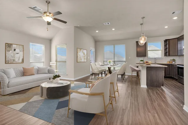 a living room with furniture a ceiling fan and a kitchen