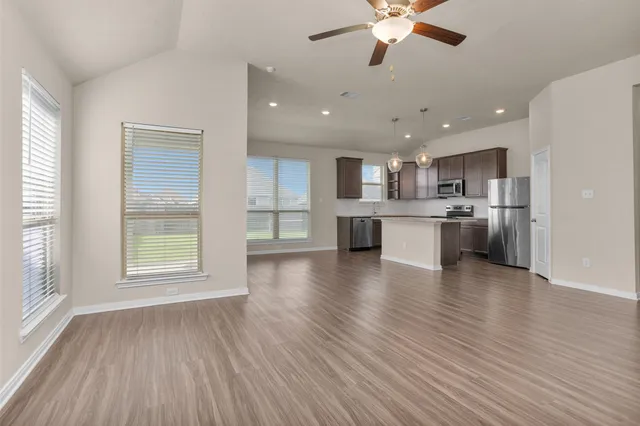 a view of a kitchen with a stove cabinets a ceiling fan and wooden floor
