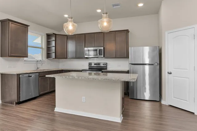 a kitchen with stainless steel appliances granite countertop a refrigerator a sink a stove a microwave and a refrigerator