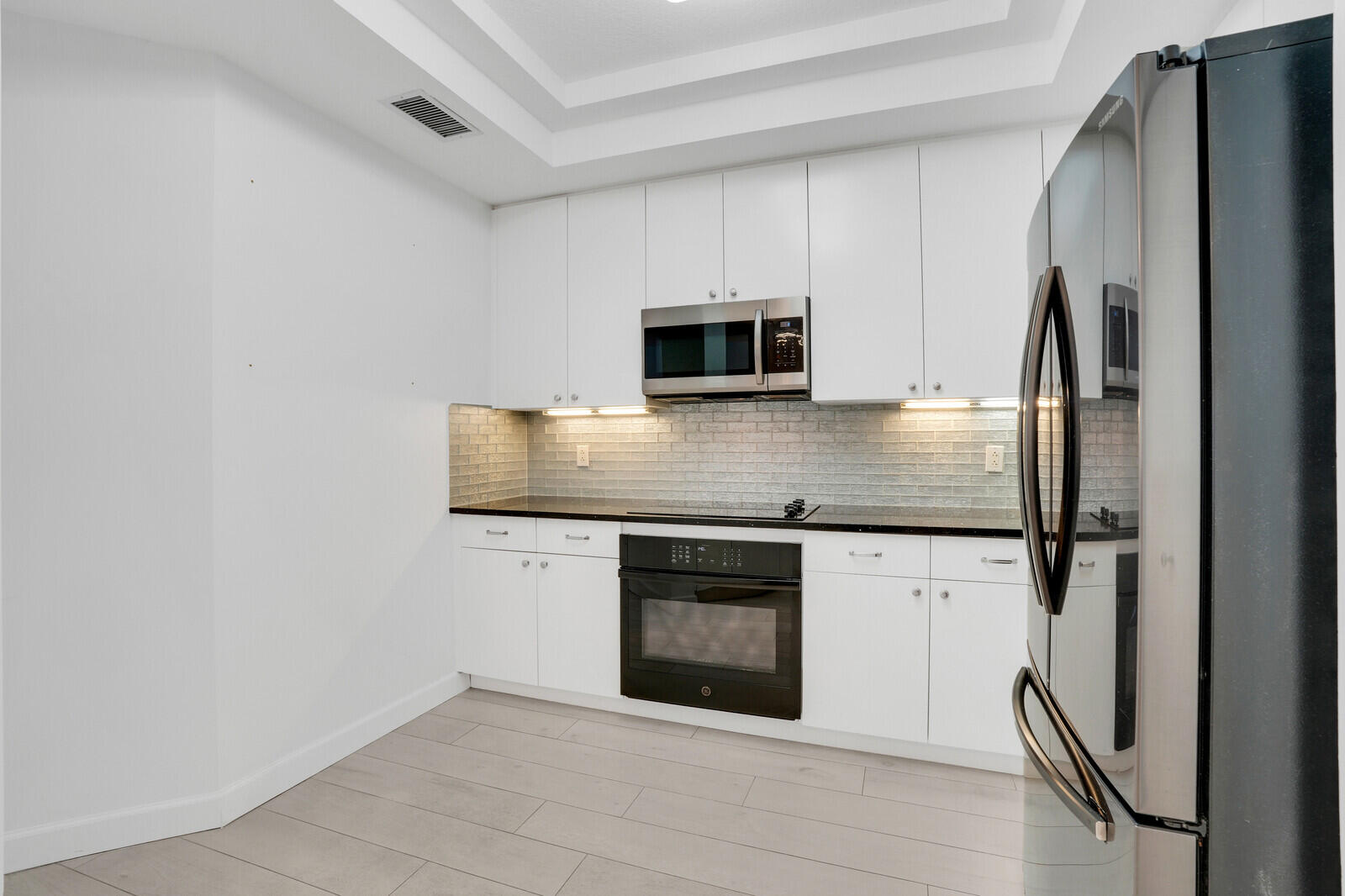 120 Ocean Grande Boulevard, Unit 2 Jupiter, FL 33477 - Photo 13 of 47 a kitchen with granite countertop white cabinets and stainless steel appliances