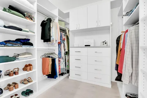 a view of walk in closet with clothes and shoes