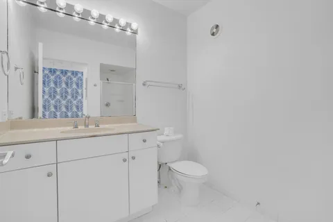 a bathroom with a granite countertop toilet a sink and a mirror