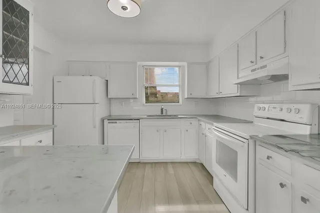 a kitchen with granite countertop white cabinets and white appliances