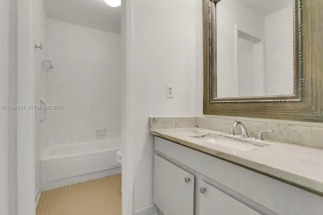 a bathroom with a granite countertop sink a mirror and a bathtub