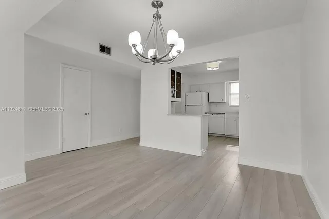 a view of a room with wooden floor chandelier and windows