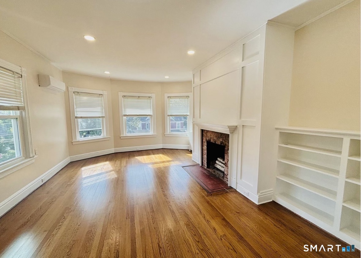 142 Broad Street Norwich, CT 06360 - Photo 10 of 26 an empty room with wooden floor fireplace and windows