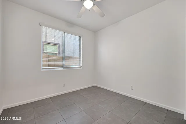 an empty room with a chandelier fan and windows