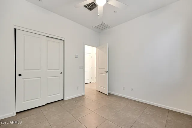 an empty room with chandelier fan and windows