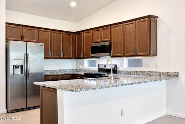 a kitchen with granite countertop a refrigerator sink and microwave