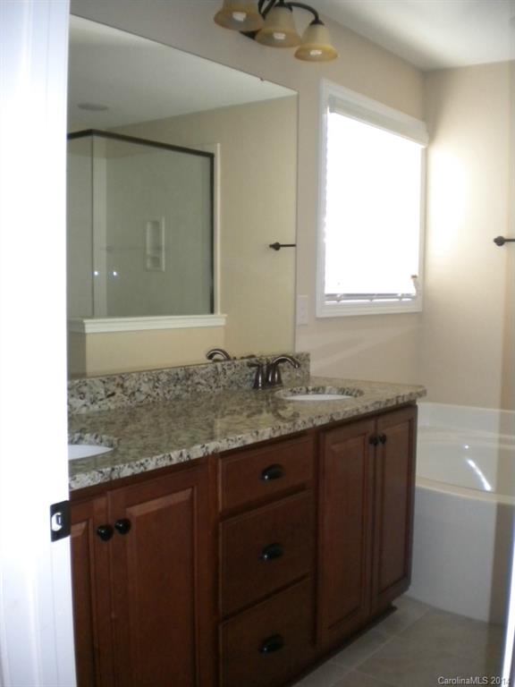 78074 Rillstone Drive, Unit 196 Lancaster, SC 29720 - Photo 19 of 24 a bathroom with a granite countertop sink a mirror and a window