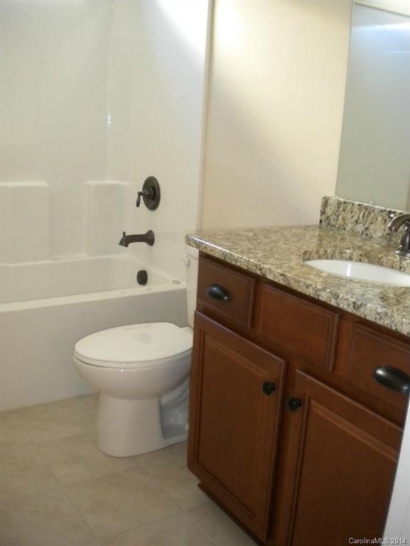 78074 Rillstone Drive, Unit 196 Lancaster, SC 29720 - Photo 21 of 24 a bathroom with a granite countertop toilet a sink and a bathtub