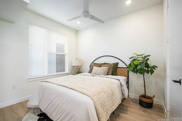 a large bed sitting in a bedroom next to a window and a potted plant