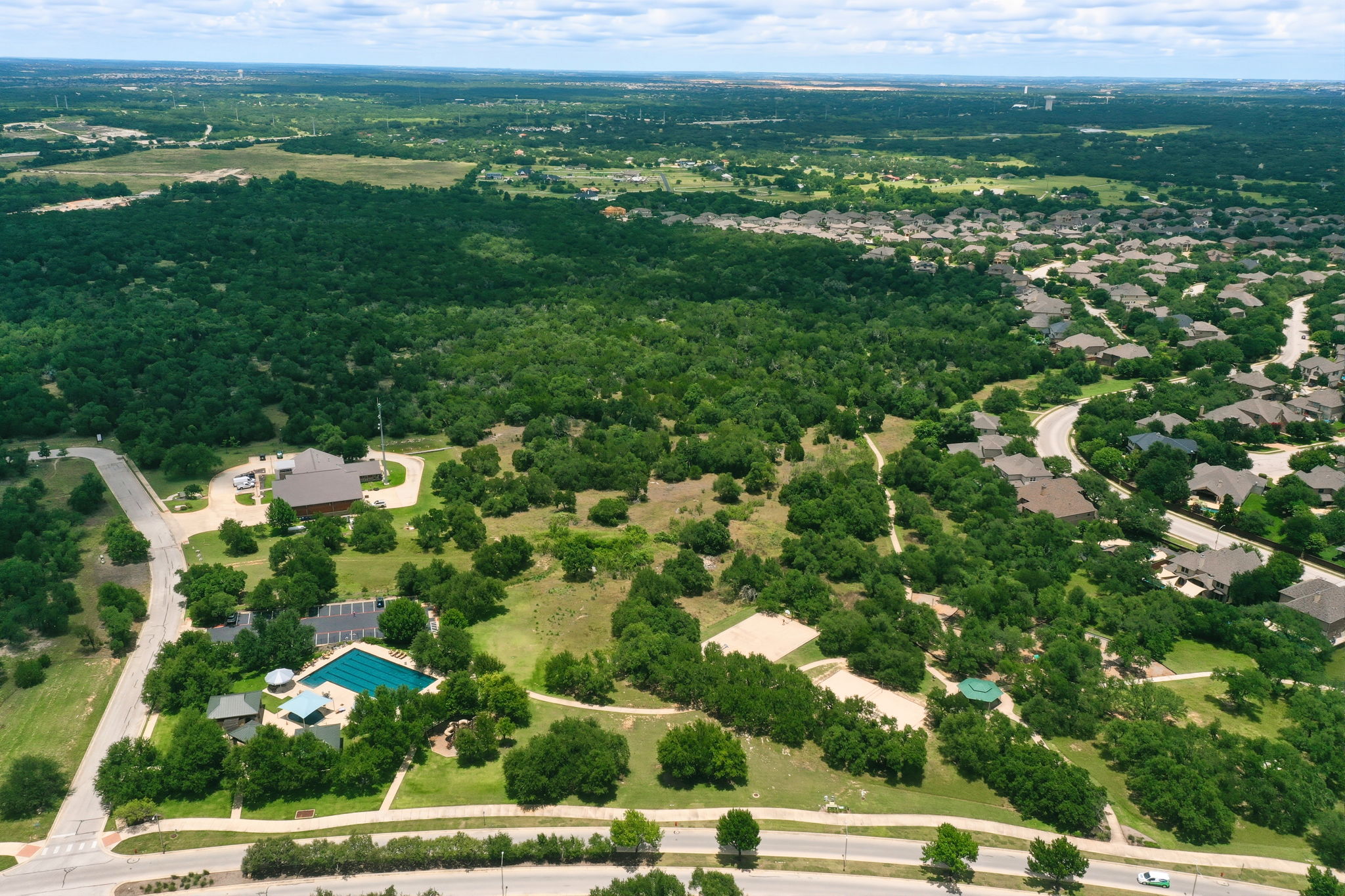 110 Dasher Drive Cedar Park, TX 78613 - Photo 37 of 39 An aerial panorama showcases a verdant community with homes nestled amidst lush trees and recreational amenities.