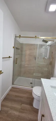 a bathroom with a granite countertop sink toilet and shower