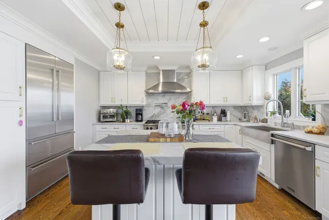 a kitchen with stainless steel appliances granite countertop a dining table chairs refrigerator and microwave