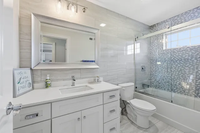 a bathroom with a sink a toilet a mirror and shower