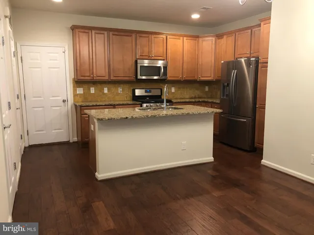 a kitchen with stainless steel appliances granite countertop a refrigerator microwave and sink