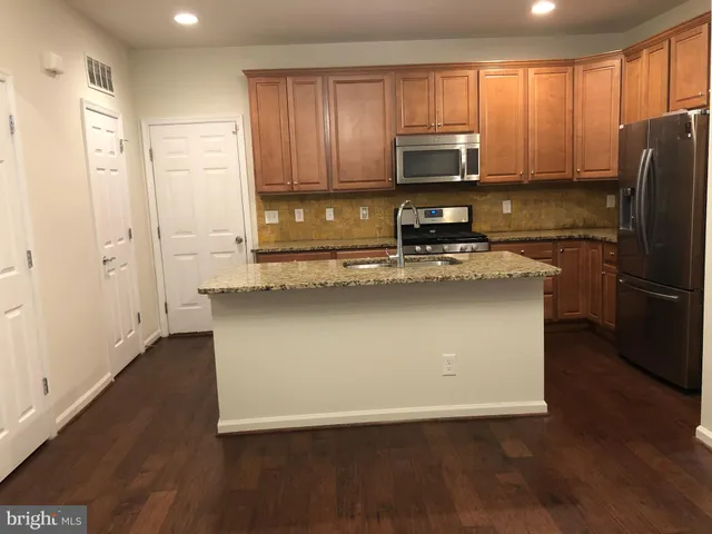 a kitchen with stainless steel appliances granite countertop a refrigerator stove a sink and dishwasher with wooden floor