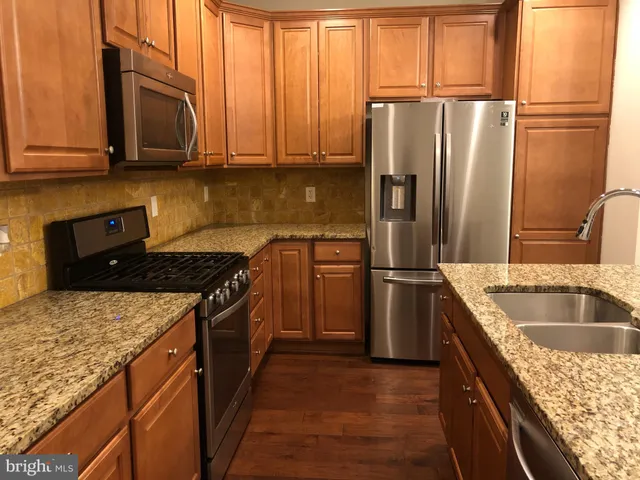a kitchen with granite countertop a sink stove and refrigerator