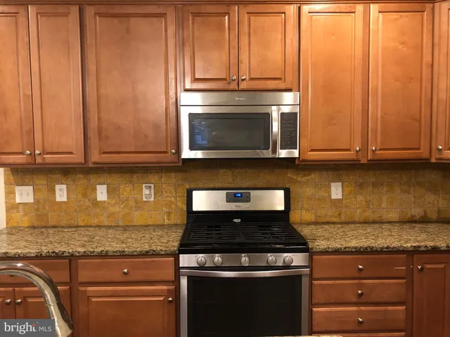 a kitchen with granite countertop wood cabinets and stainless steel appliances