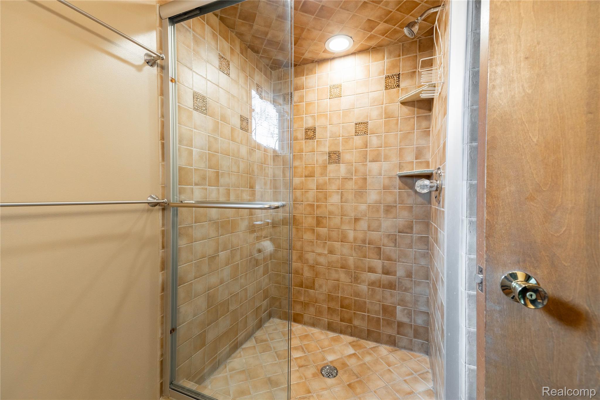 7611 Ferry Road Grosse Ile, MI 48138 - Photo 36 of 51 Glass-enclosed shower featuring full-height tile surround with decorative accents, built-in shelving, recessed lighting, and a coordinating tiled floor