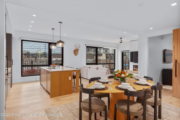 a kitchen with stainless steel appliances granite countertop wooden cabinets a stove a sink a dining table and chairs