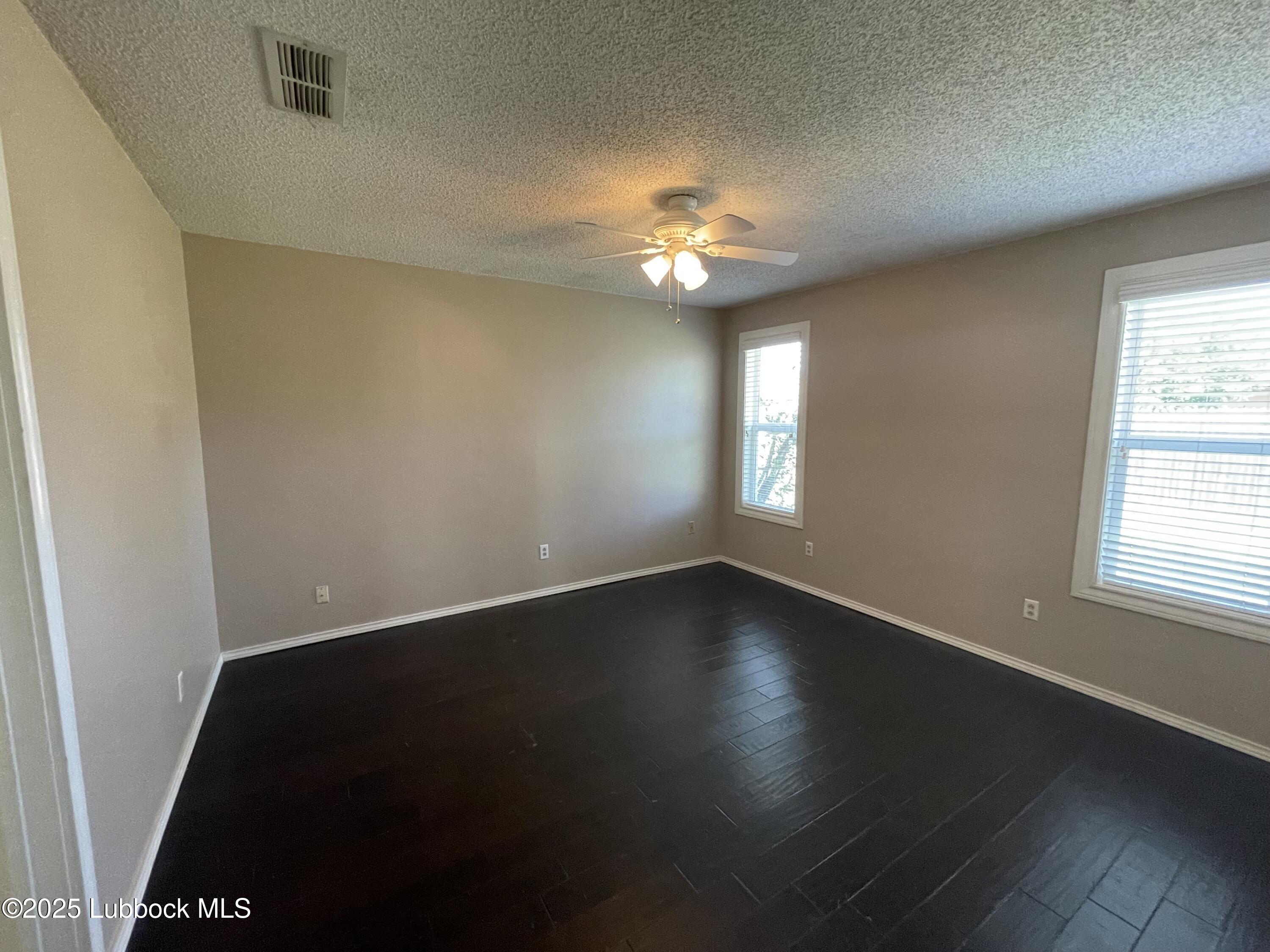 6619 Huron Avenue Lubbock, TX 79424 - Photo 8 of 10 an empty room with wooden floor and windows