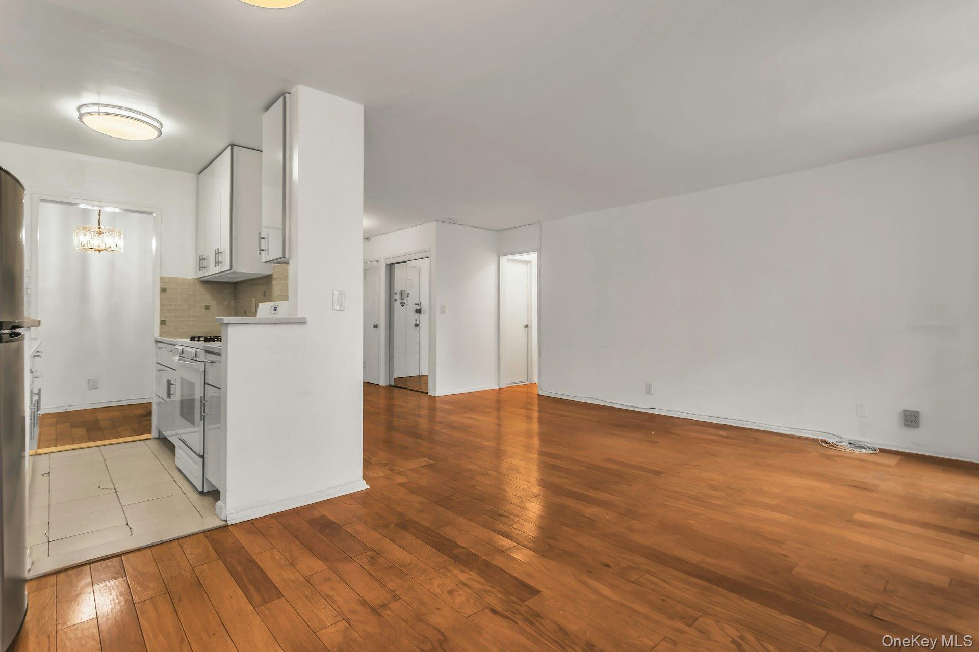 138-10 Franklin Avenue, Unit 9J Queens, NY 11355 - Photo 11 of 25 Kitchen featuring white cabinets, light wood-type flooring, light countertops, white gas range oven, and backsplash