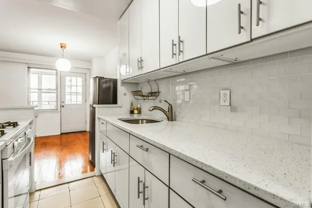a kitchen with stainless steel appliances granite countertop a sink a stove and white cabinets