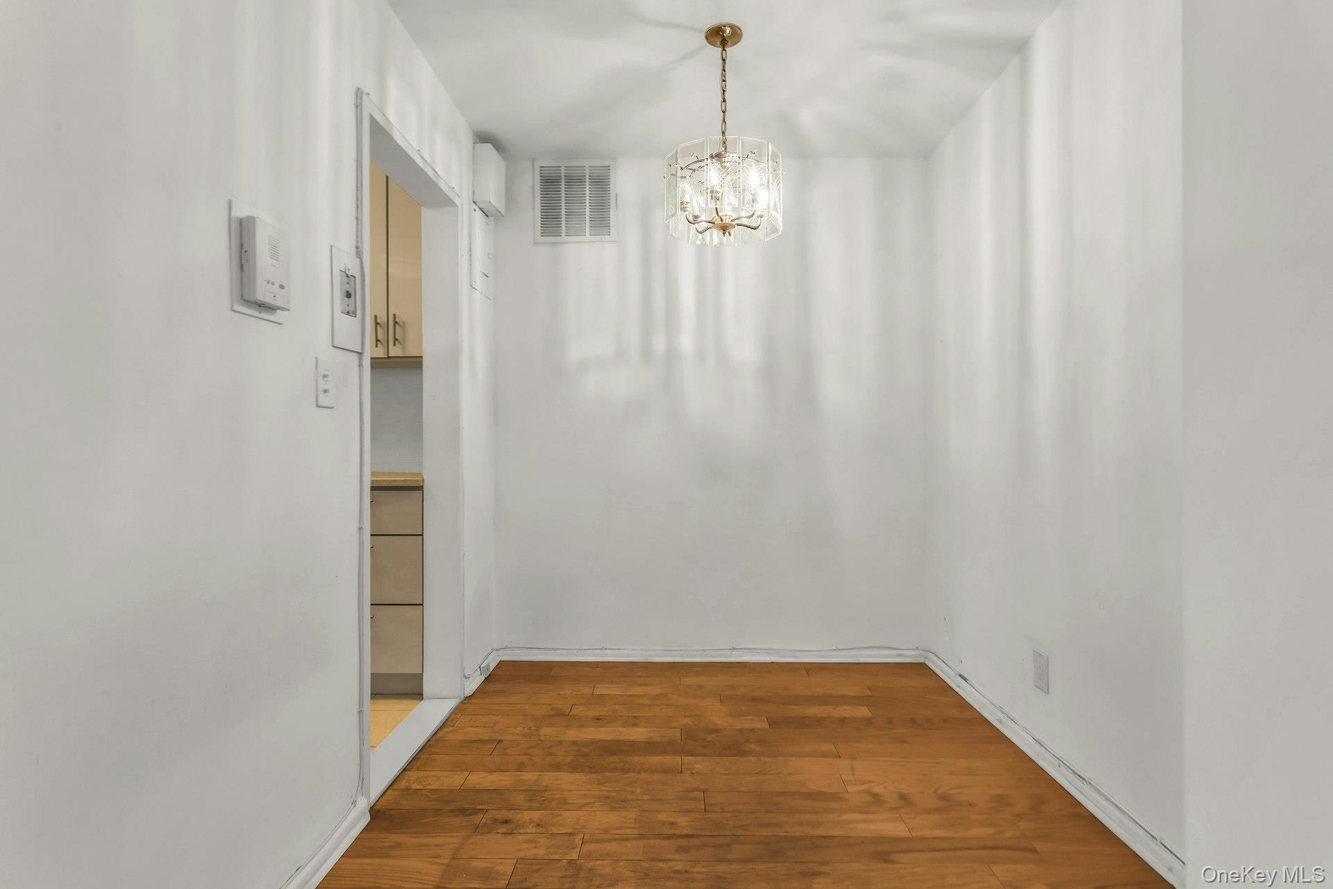 138-10 Franklin Avenue, Unit 9J Queens, NY 11355 - Photo 17 of 25 Unfurnished dining area featuring light wood-style floors and a chandelier