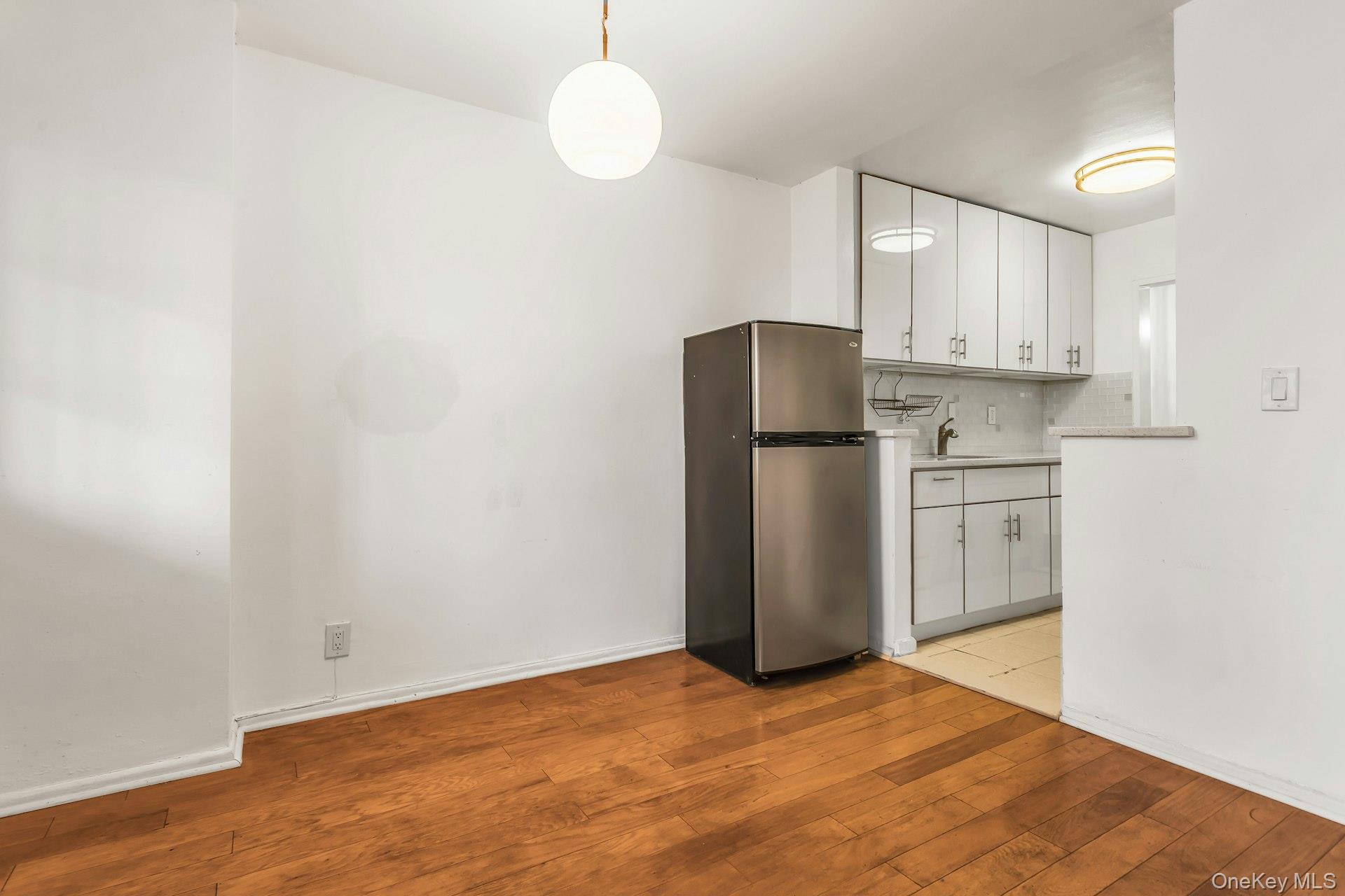 138-10 Franklin Avenue, Unit 9J Queens, NY 11355 - Photo 10 of 25 Kitchen featuring white cabinetry, freestanding refrigerator, light countertops, decorative backsplash, and pendant lighting