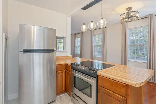 a kitchen with stainless steel appliances granite countertop a refrigerator a oven a sink and a chandelier