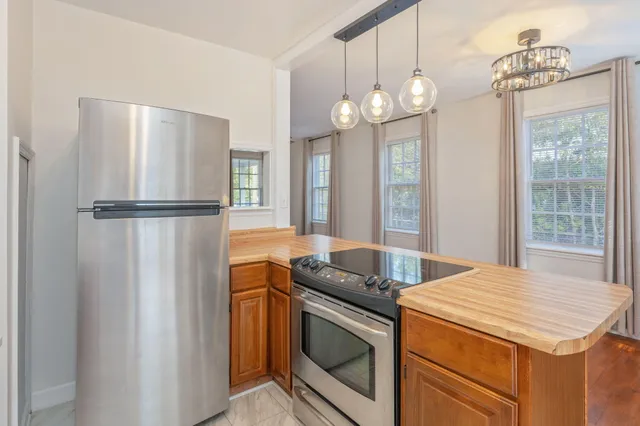 a kitchen with stainless steel appliances granite countertop a refrigerator a oven a sink and a chandelier