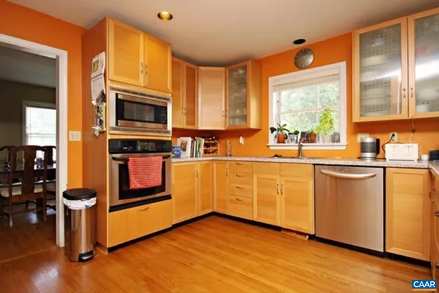 a kitchen with stainless steel appliances a sink cabinets and wooden floor