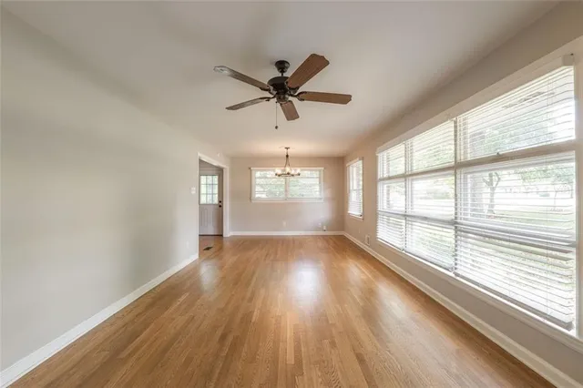 a view of empty room with wooden floor and kitchen view