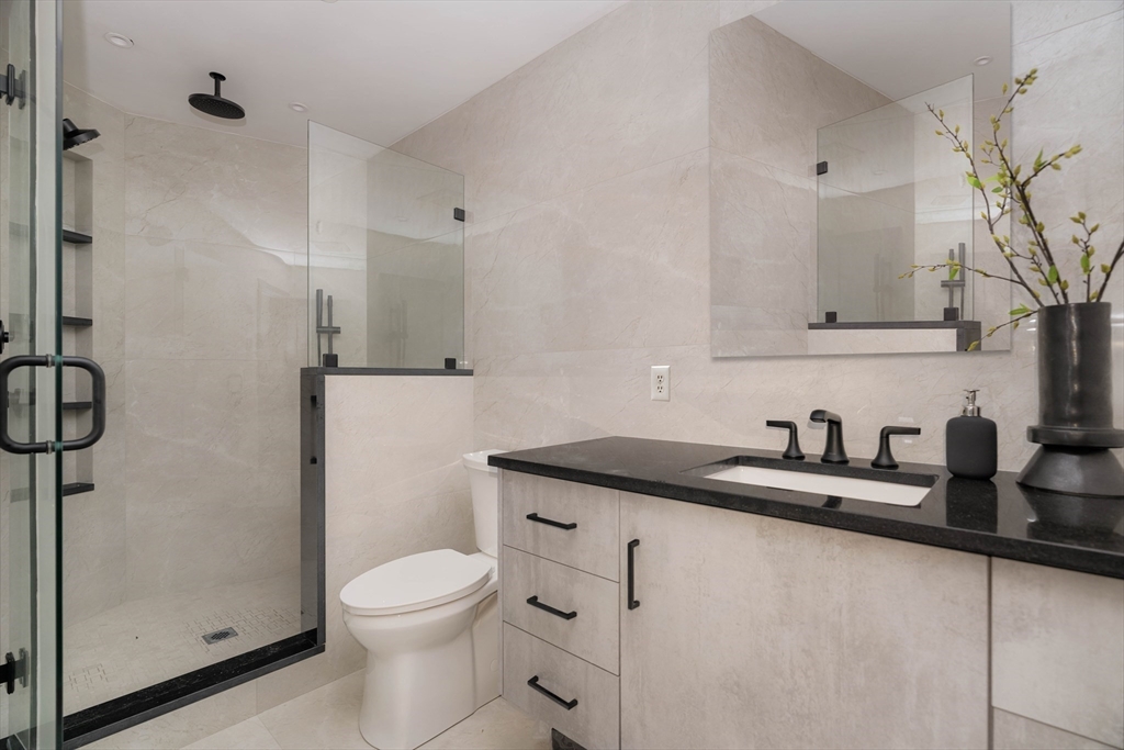 31 Highland Road, Unit 1 Brookline, MA 02445 - Photo 19 of 34 a bathroom with a granite countertop sink a toilet and a shower