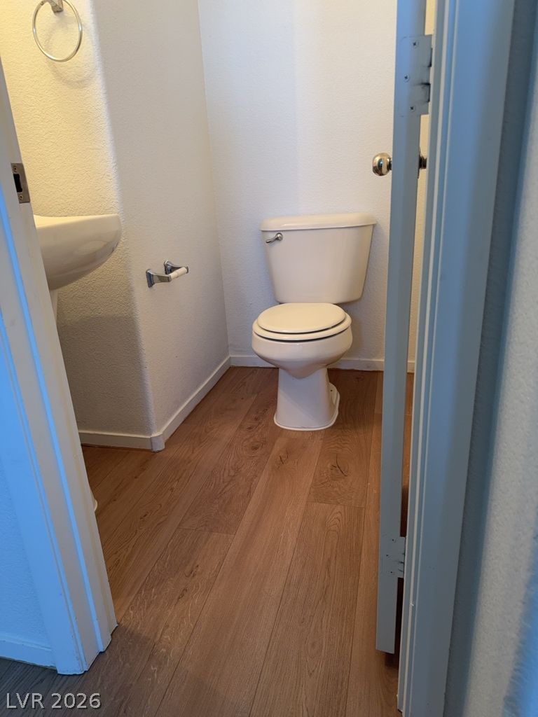 4790 Pinon Pointe Road Las Vegas, NV 89115 - Photo 7 of 16 A compact half-bath features hardwood-style flooring and a pedestal sink.