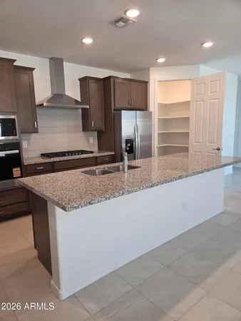 a kitchen with kitchen island granite countertop a sink a counter top space and cabinets