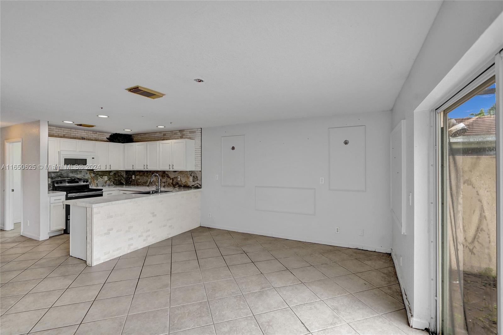 6073 Spring Isles Boulevard Lake Worth, FL 33463 - Photo 11 of 66 a kitchen with a refrigerator and white cabinets