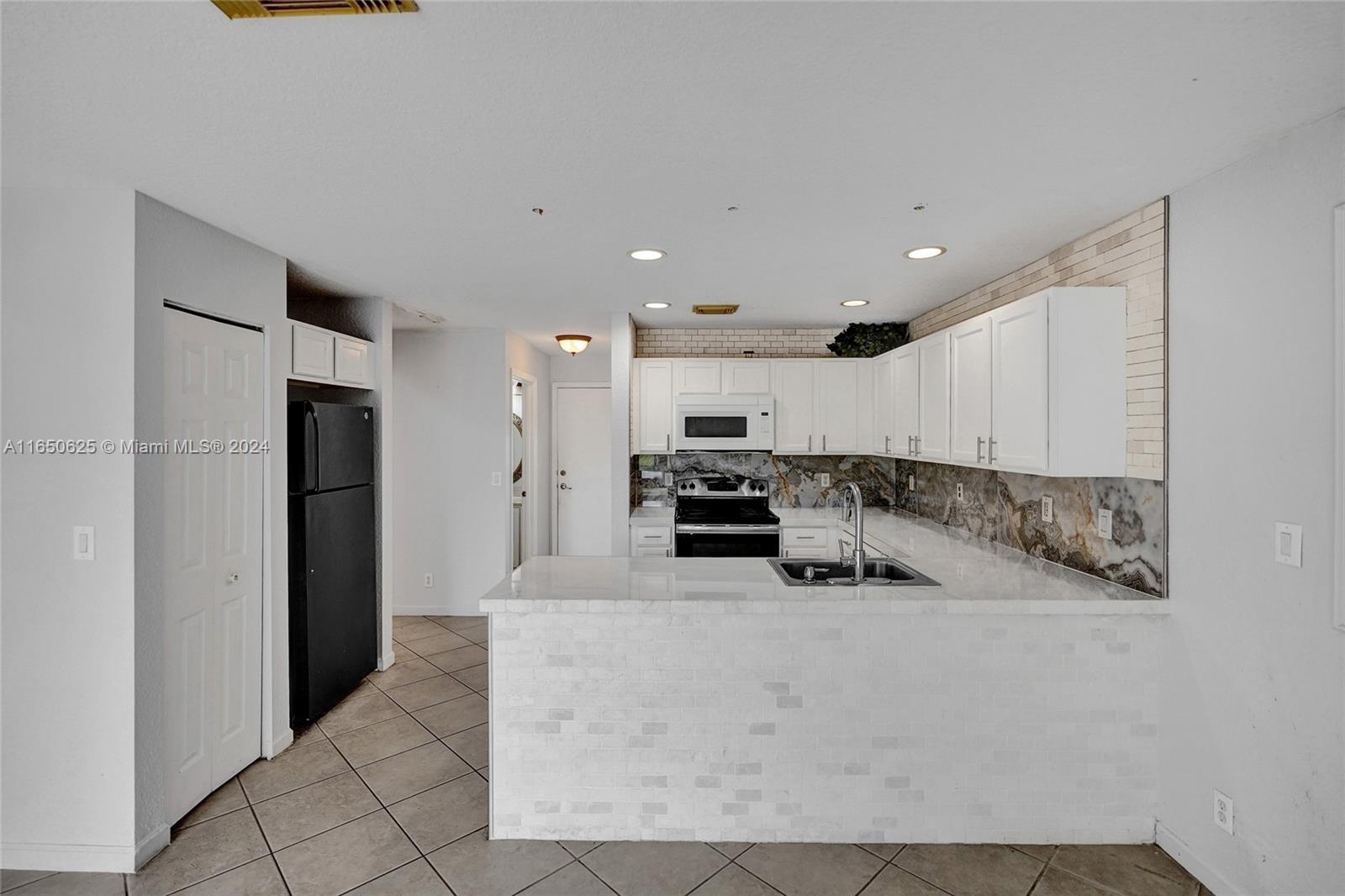 6073 Spring Isles Boulevard Lake Worth, FL 33463 - Photo 15 of 66 a kitchen with stainless steel appliances kitchen island granite countertop a refrigerator and a sink