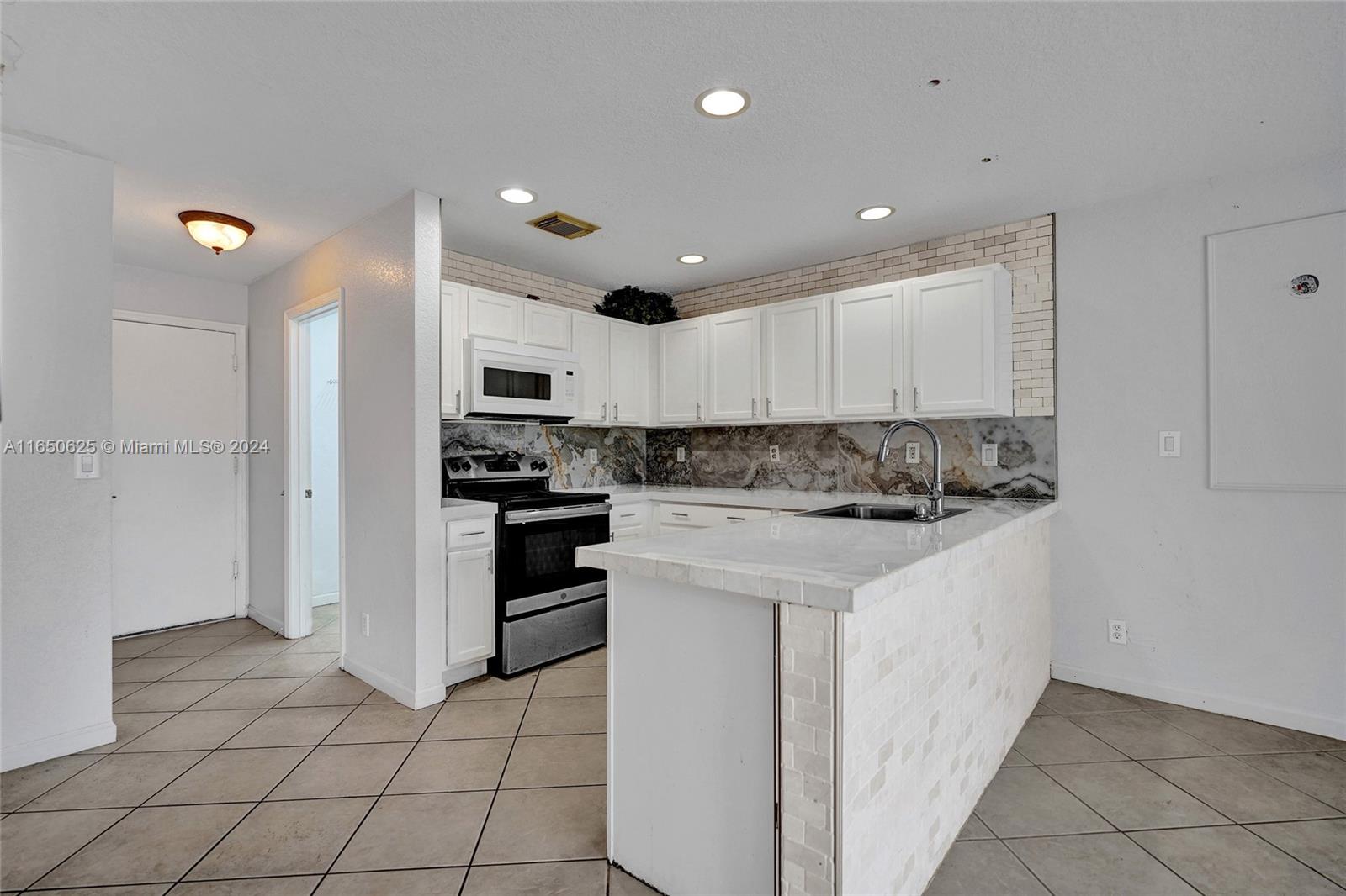 6073 Spring Isles Boulevard Lake Worth, FL 33463 - Photo 16 of 66 a kitchen with stainless steel appliances granite countertop a refrigerator and a stove top oven