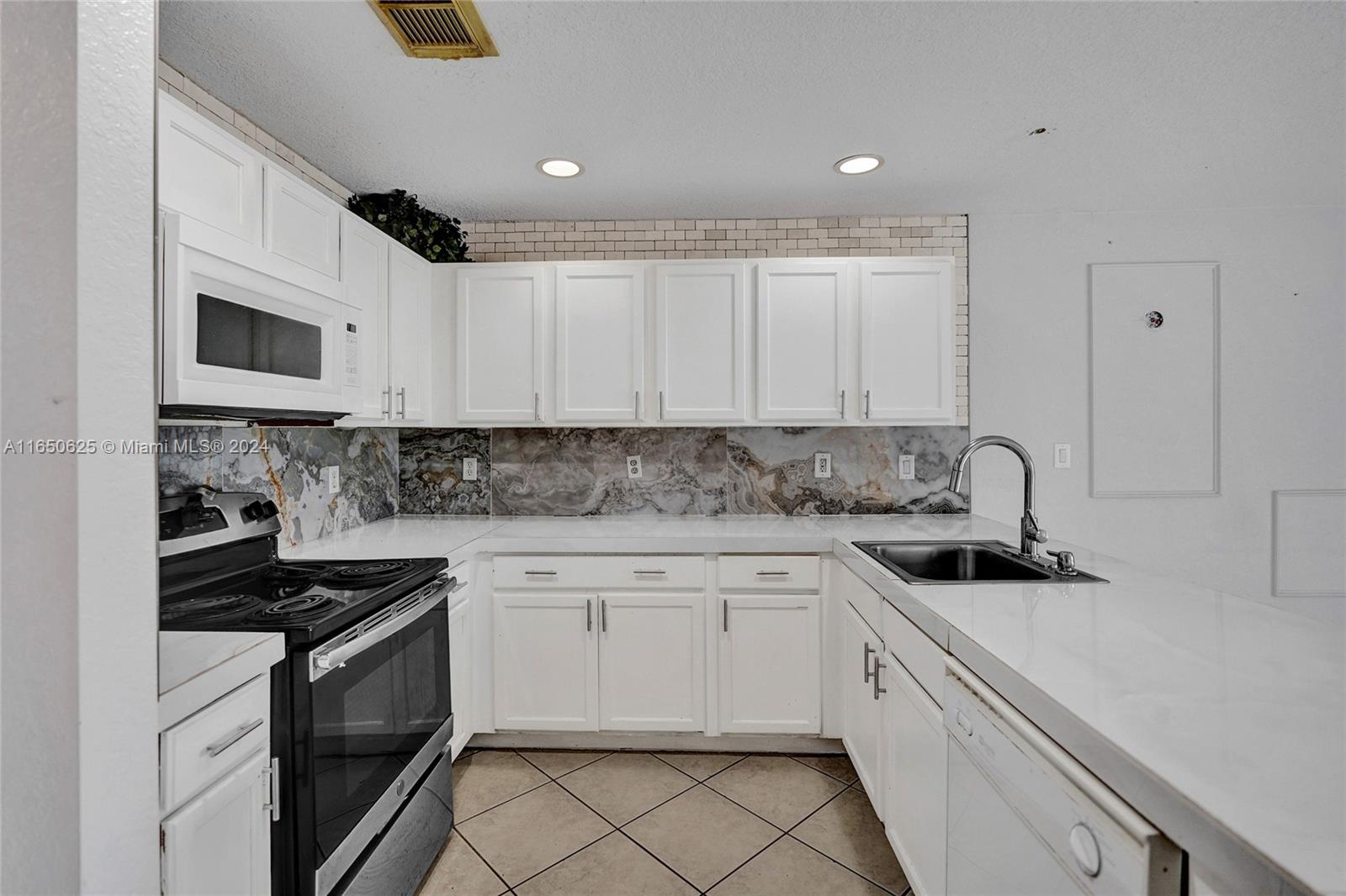 6073 Spring Isles Boulevard Lake Worth, FL 33463 - Photo 17 of 66 a kitchen with white cabinets stainless steel appliances and sink