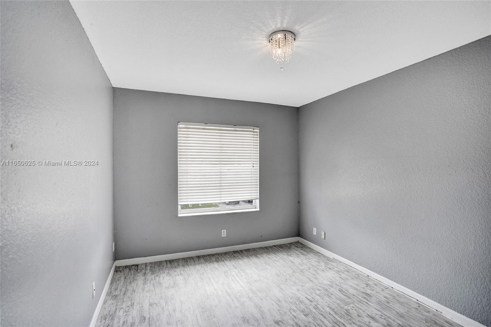 6073 Spring Isles Boulevard Lake Worth, FL 33463 - Photo 31 of 66 an empty room with wooden floor and windows