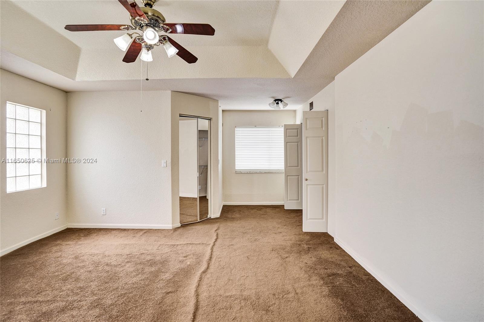 6073 Spring Isles Boulevard Lake Worth, FL 33463 - Photo 34 of 66 an empty room with chandelier fan and windows
