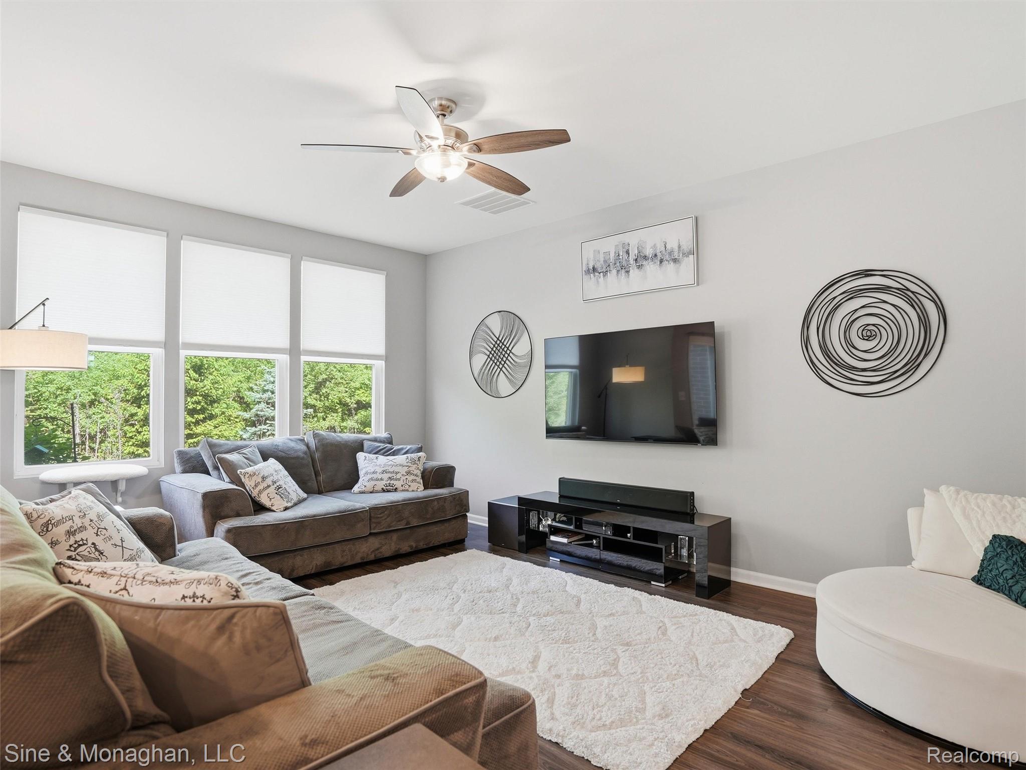 24827 Ivy Road Novi, MI 48375 - Photo 10 of 38 Living space featuring wood-finish flooring, a ceiling fan with integrated lighting, and multiple windows with roller shades