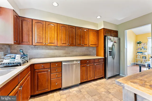 a kitchen with stainless steel appliances granite countertop wooden cabinets a sink and a refrigerator