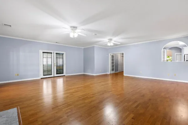 a view of an empty room with wooden floor and a window